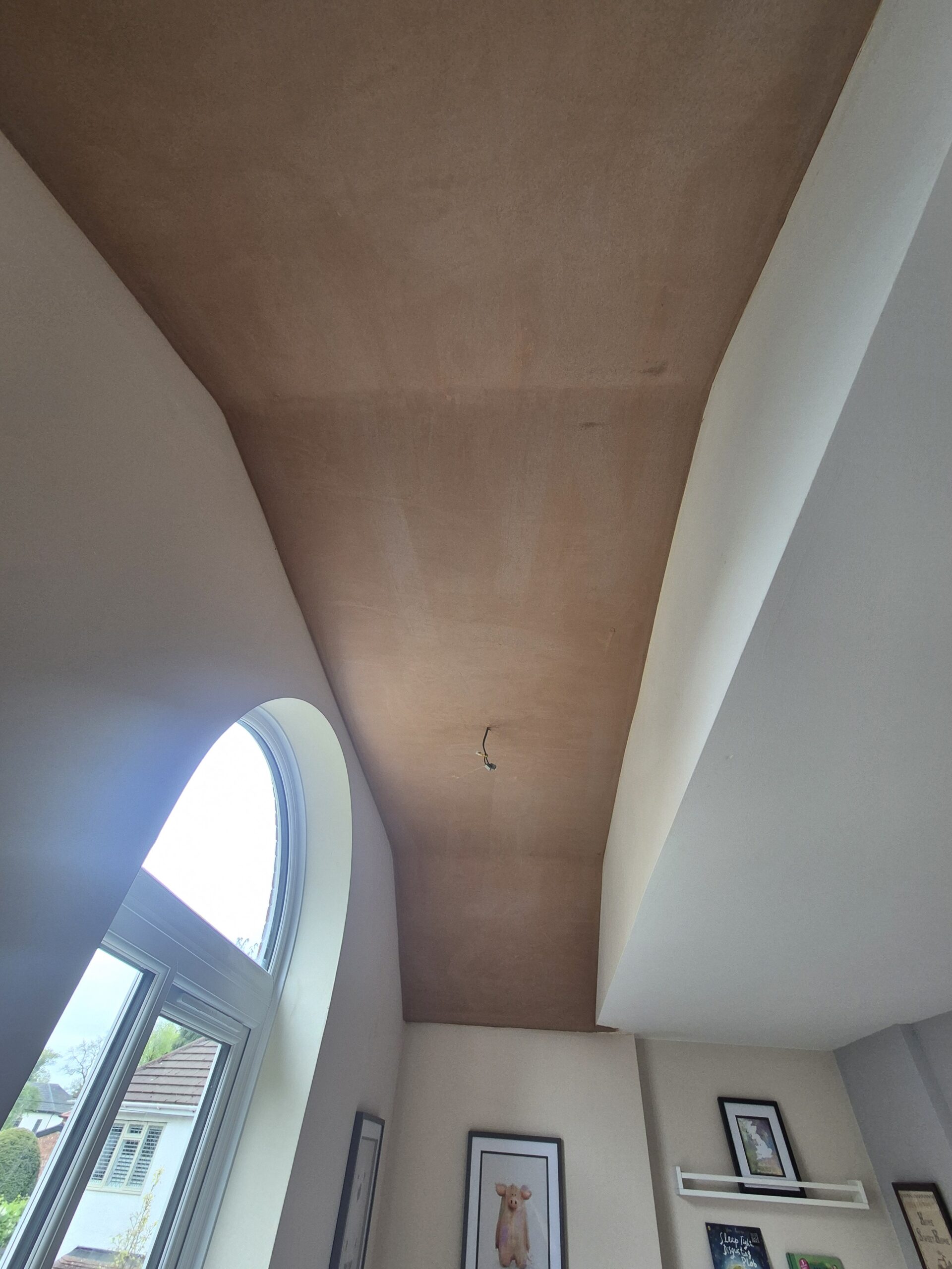 Fresh plaster finish across a curved ceiling beside an arched window