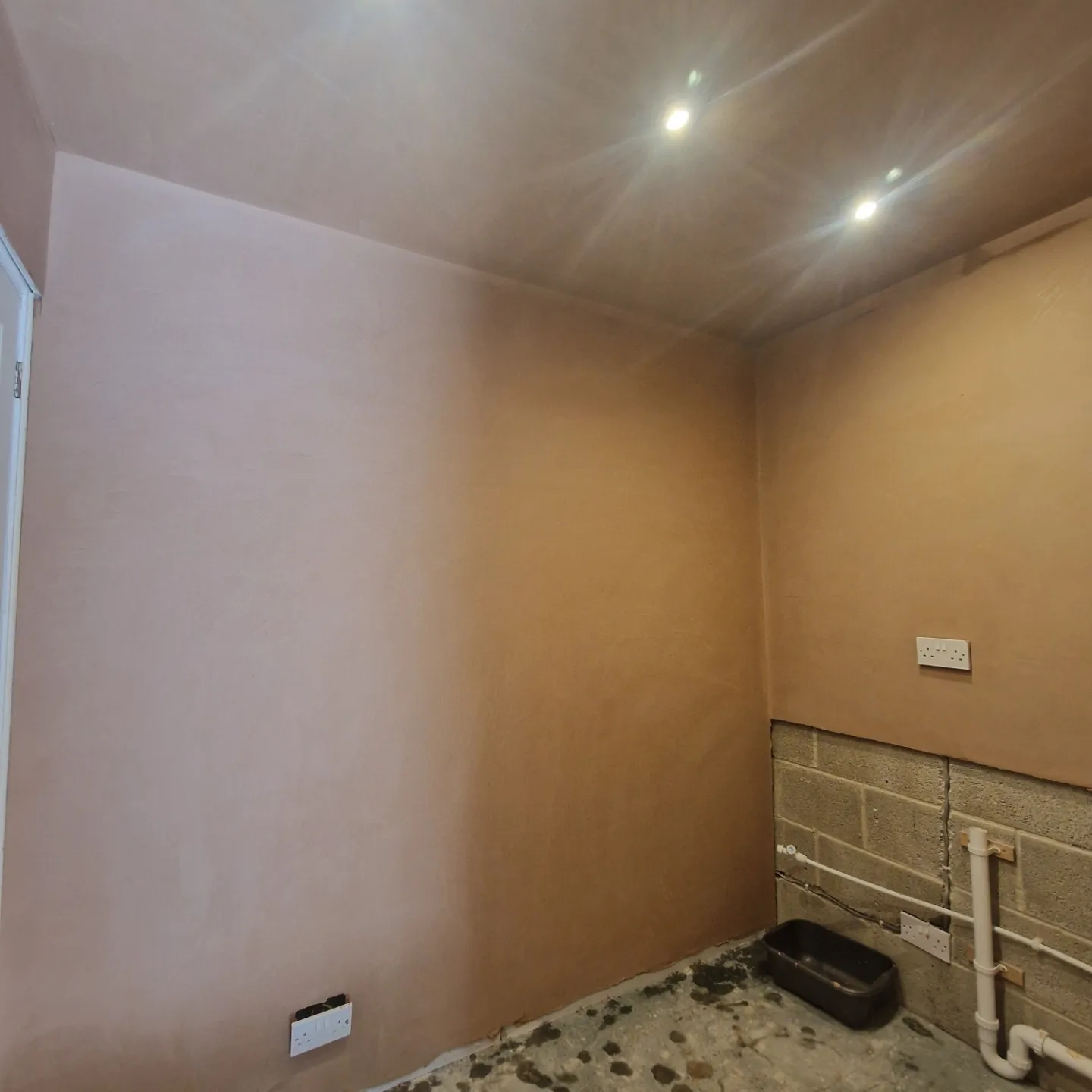 Room with freshly plastered walls and ceiling around recessed lights